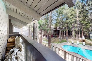 A balcony with a view of a swimming pool, surrounded by trees. - 🏔 Cozy Mountain Condo in Mammoth Lakes | Sleeps 6 | Shared Hot Tub 🌲 (Mammoth Lakes)