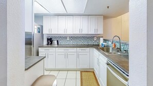 A compact kitchen with white cabinets, a stainless steel sink, and a tiled backsplash. - Ski-in/out condo with mountain view, private hot tub, deck & fireplace (Mammoth Lakes)
