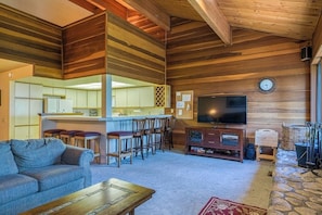 A spacious living area with a sofa, a coffee table, a TV, and a stone fireplace. - Mammoth Lakes getaway - walking distance to the slopes (Mammoth Lakes)