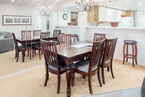 Ein Essbereich mit Holztisch und -stühlen, einer Chandelier und einer Küche im Hintergrund.
