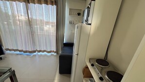 A compact kitchen with a refrigerator, stove, and a small dining area. - Moradas Dom Goulart  (Palhoça)