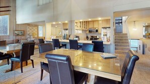 Una cocina moderna con electrodomésticos integrados, un comedor con mesa de vidrio y una escalera que sube a otro nivel.