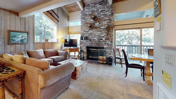 Un salón acogedor con chimenea, muebles de madera y ventanas amplias.