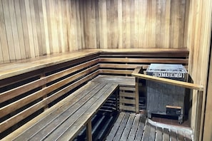 A sauna with wooden benches and a warning sign on the heater. - Delightful Dog-Friendly Condo with a Shared Pool, Sauna, and Hot Tub (Mammoth Lakes)