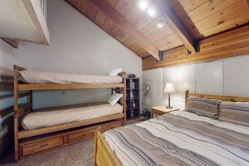 Een kamer met stapelbedden, een boekenkast, een lamp en een ventilator.