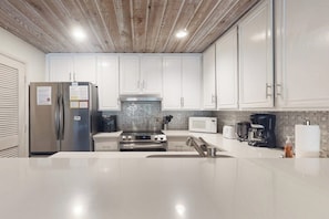 A modern kitchen with white cabinets, stainless steel appliances, and a wooden ceiling. - A Serene Destination with Shared Pool, Sauna, and Hot Tub (Mammoth Lakes)