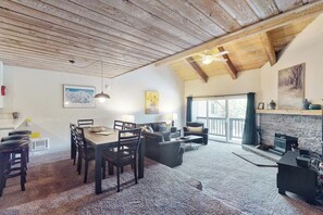 A spacious living area with a wooden ceiling, a dining table with chairs, a sofa, and a fireplace. - A Serene Destination with Shared Pool, Sauna, and Hot Tub (Mammoth Lakes)