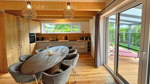 Una cocina moderna con comedor, piso de madera y ventanas amplias.