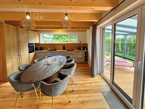 Eine moderne Küche mit Essbereich, Holzboden und großen Fenstern.