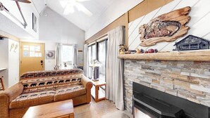 A living room with a sofa, fireplace, and a ceiling fan. - Cozy Studio with a Loft, Shared Swimming Pool, Hot Tub, and Sauna (Mammoth Lakes)