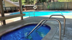 En lille, rektangulær pool med en metalstige, omgivet af en betonflisebelagt terrasse og et træhegn.