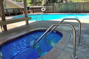 A small, rectangular pool with a metal ladder, surrounded by a concrete deck and a wooden fence. - Mountain-view, two-level studio with decks, pool & hot tub - close to skiing (Mammoth Lakes)