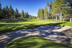A golf course with a clear path, sand bunkers, and tall trees. - Mountain-view, two-level studio with decks, pool & hot tub - close to skiing (Mammoth Lakes)