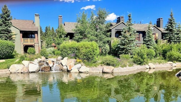 A lakeside resort with multiple cabins, a pond, and surrounding greenery. - Enjoy this Beautiful Lodge Near the Golf Course, Athletic Club, & the Slopes (Mammoth Lakes)