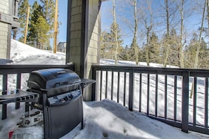 A barbecue grill on a balcony with snow on the ground and trees in the background. - Mountain Getaway with a Shared Outdoor Pool, Hot Tub and Nature Views (Mammoth Lakes)