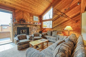 Ein gemütliches Wohnzimmer mit Kamin aus Stein, Holzboden und großen Fenstern.