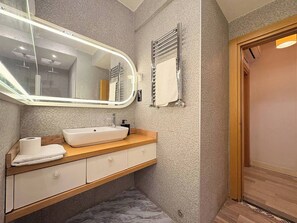 A bathroom with a large mirror, a sink, a towel, and a shower area. - Taksim Square1br Suite 02 (Istanbul)