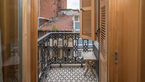 A narrow corridor leading to a balcony with a patterned floor, a small table, and a metal railing. - Taksim Square1br Suite 02 (Istanbul)