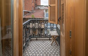 A narrow corridor leading to a balcony with a patterned floor, a small table, and a metal railing. - Taksim Square1br Suite 02 (Istanbul)