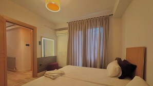 A hotel room with two beds, a wooden headboard, a mirror, a radiator, and a door leading to another room. - Taksim Square1br Suite 02 (Istanbul)