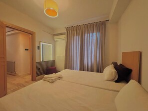 A hotel room with two beds, a wooden headboard, a mirror, a radiator, and a door leading to another room. - Taksim Square1br Suite 02 (Istanbul)