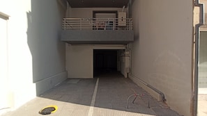 A narrow corridor with a metal railing on the upper level, leading to a door at the end.