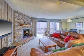 Ein Wohnzimmer mit Kamin aus Stein, Ledersofa, Couchtisch aus Holz und einem an der Wand befestigten Fernseher.