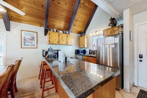 A kitchen with granite countertops, wooden cabinets, a stainless steel refrigerator, and a wooden ceiling. - Spacious, updated townhouse with deck & sauna (Mammoth Lakes)
