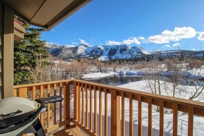 A wooden deck with a grill, overlooking a snow-covered landscape with mountains. - Creekside townhome with shared hot tub, deck offering panoramic views (Mammoth Lakes)