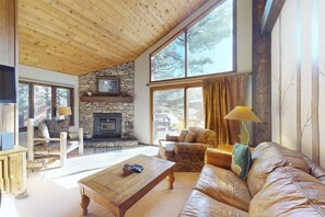 Ein gemütliches Wohnzimmer mit Kamin aus Stein, einer Ledersofa und einem Holztisch.