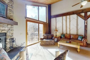 Ein Wohnzimmer mit Kamin aus Stein, einer Sofagarnitur, einem Couchtisch und einem großen Fenster.