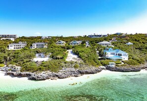 Une propriété située sur la côte, comprenant plusieurs maisons, une plage de sable fin et une côte rocheuse.