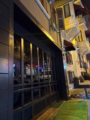 A building with large windows, a balcony with plants, and a sign indicating a restaurant. - Taksim Square1 Bedroom Suite 03 (Istanbul)