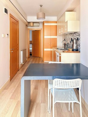 A modern kitchen with a central island, wooden cabinets, and a white chair. - Taksim Square1 Bedroom Suite 03 (Istanbul)