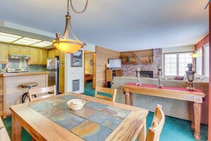 A compact kitchen with modern appliances, a dining area with a table and chairs, and a cozy living space with a fireplace. - Updated Rental with Shared Hot Tub & Pool, Updated Kitchen (Mammoth Lakes)