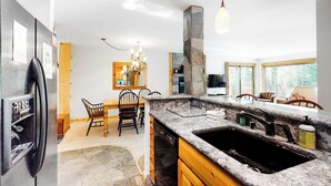 Eine Küche mit Granit Arbeitsplatten, einer Steinsäule, einem Essbereich mit Stühlen und einem großen Fenster.