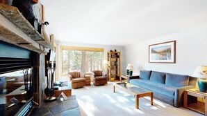 Ein Wohnzimmer mit Kamin, Sofa, Sesseln und Bücherregal.