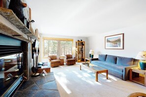 A living room with a fireplace, sofa, armchairs, and a bookshelf. - Condo with Shared Hot Tubs, Pool, and Sauna & Great Mountain Views (Mammoth Lakes)