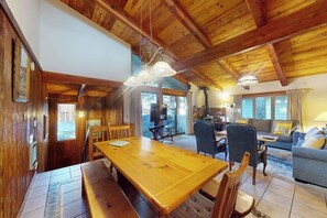 Ein Holzinterieur mit Esstisch, Stühlen, einer Couch und einem Kamin.