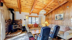 A cozy living room with a fireplace, wooden ceiling, and a sofa with cushions. - Central Condo w/ Fireplace & Shared Pool/Hot Tub/Tennis - 1 Mile to Gondola (Mammoth Lakes)