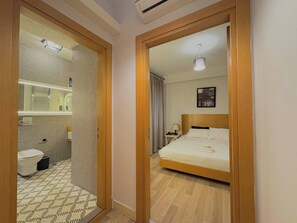 Ein Hotelzimmer mit einem hölzernen Bett, einem Badezimmer mit Toilette und Waschbecken sowie einem Spiegel.