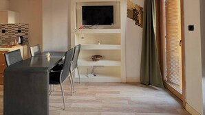 Sala de estar moderna com área de jantar, televisão de tela plana na parede, porta de madeira e painel de azulejos.