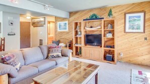 Ein Wohnzimmer mit einer Couch, einem Couchtisch, einer Holzunterhaltungseinheit und einem an der Wand montierten Fernseher.