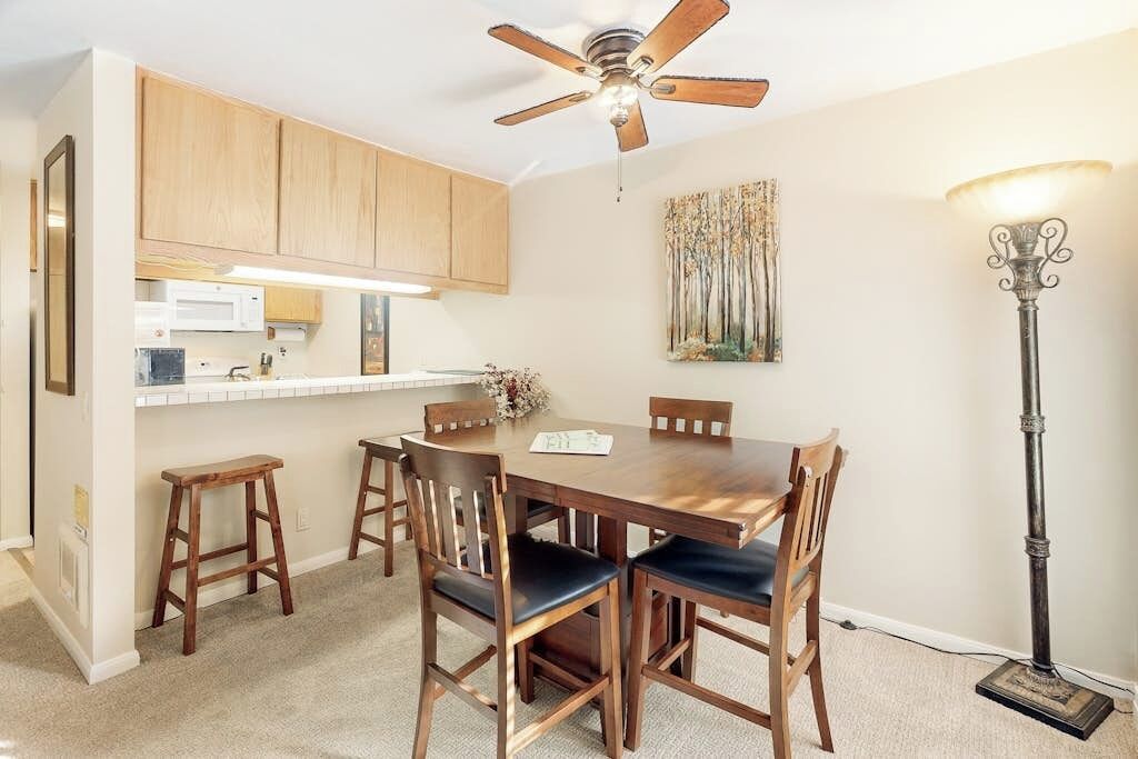 A dining area with a wooden table and chairs, a ceiling fan, and a floor lamp.