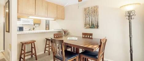 A dining area with a wooden table and chairs, a ceiling fan, and a floor lamp.