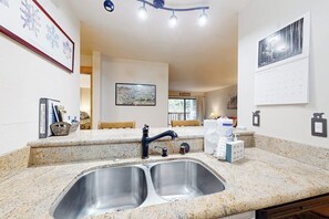 A kitchen with a double sink, granite countertops, a map on the wall, and a calendar. - Cozy Retreat with Patio, WiFi, Shared Pool, Hot Tub & Sauna - Near Slopes & Golf (Mammoth Lakes)