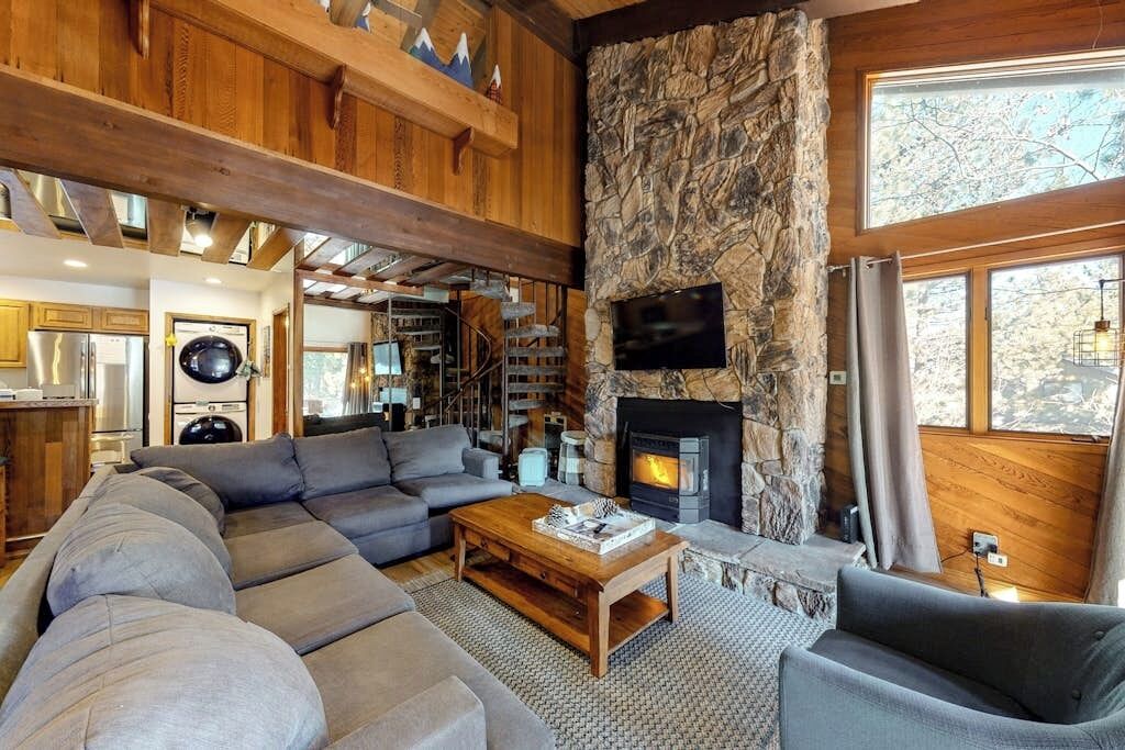 Ein gemütliches Wohnzimmer mit Kamin aus Stein, einer großen Couch und einem an der Wand befestigten Fernseher.