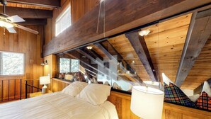 Una camera da letto con un letto, una lampada, una finestra e una ventola a soffitto.