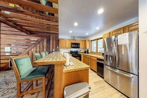 Eine Küche mit Holzausstattung, einem Edelstahlkühlschrank und einem Essbereich mit Holztisch und Stühlen.