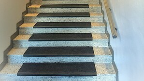 Un escalier avec une rampe, des panneaux muraux en bois et une porte sur laquelle est apposé un panneau « interdiction de fumer ».